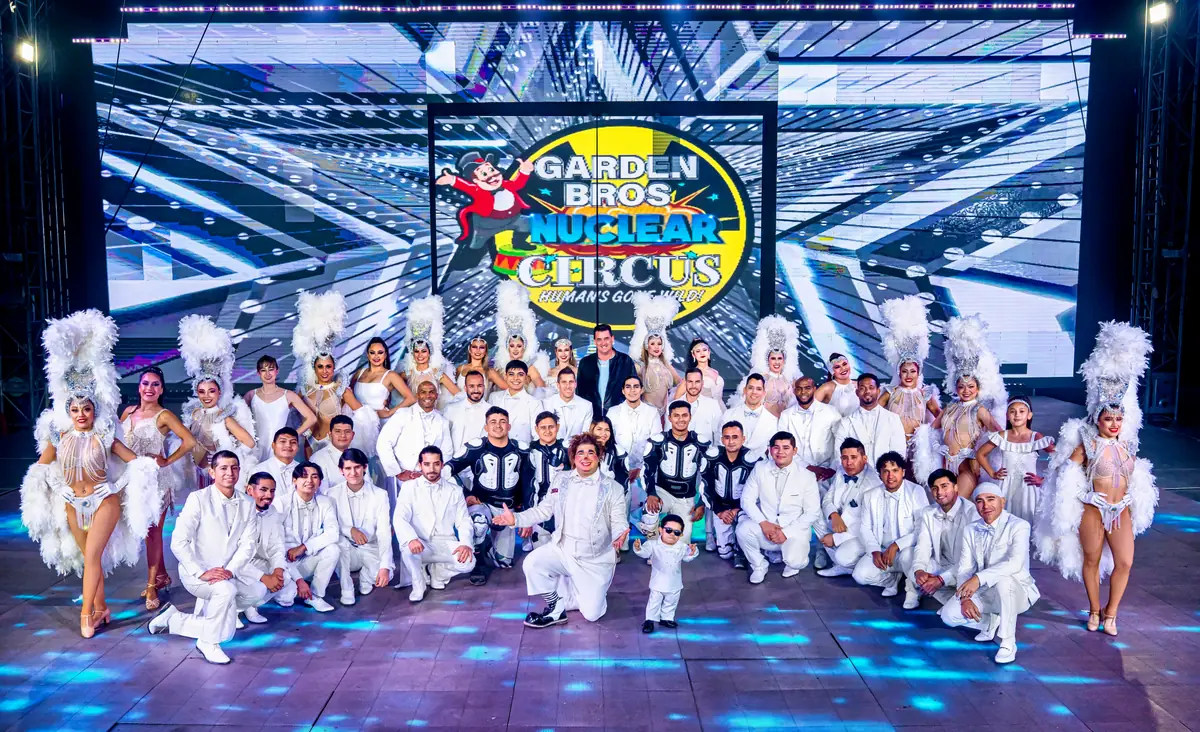The full Garden Bros Nuclear Circus cast on stage in front of the Nuclear Circus logo